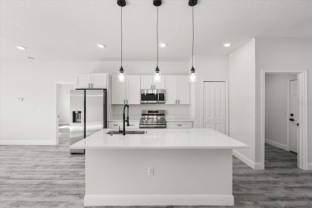16057 SW 17th Ave, Ocala, FL 34473 - kitchen with appliances with stainless steel finishes, a textured ceiling, light wood finished floors, white cabinets, and a kitchen island with sink
