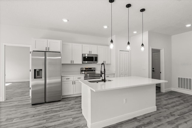 16057 SW 17th Ave, Ocala, FL 34473 - kitchen with stainless steel appliances, light wood finished floors, white cabinets, light countertops, and a textured ceiling