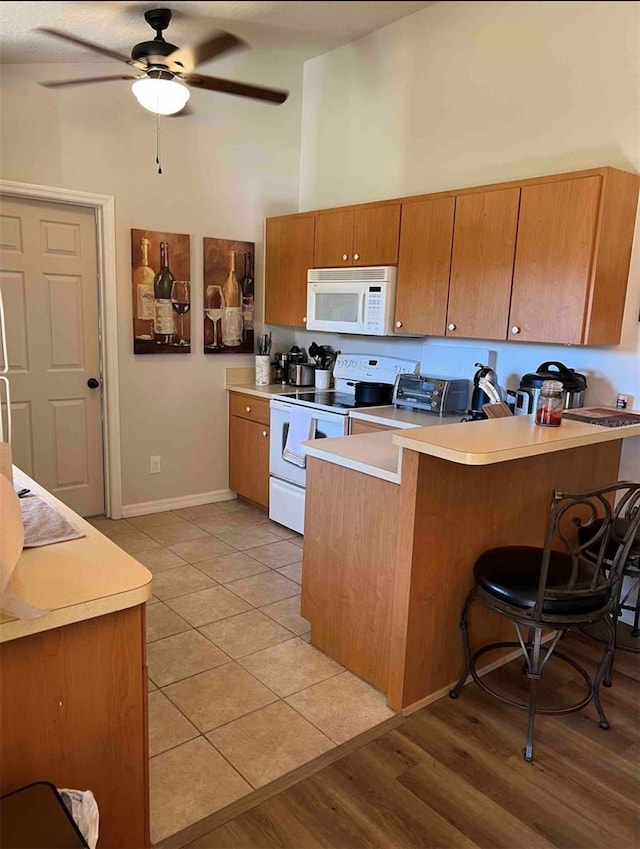4805 SW 171st Ct, Dunnellon, FL 34432 - kitchen with white appliances, a peninsula, light countertops, ceiling fan, and a breakfast bar area