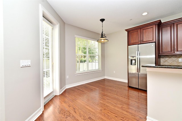1649 Lake Baldwin Ln, Orlando, FL 32814 - kitchen with stainless steel fridge, dark countertops, wood finished floors, decorative backsplash, and decorative light fixtures