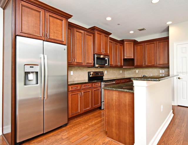 1649 Lake Baldwin Ln, Orlando, FL 32814 - kitchen featuring stainless steel appliances, light wood finished floors, tasteful backsplash, brown cabinets, and recessed lighting