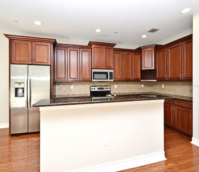 1649 Lake Baldwin Ln, Orlando, FL 32814 - kitchen featuring appliances with stainless steel finishes, light wood-style flooring, a kitchen island with sink, recessed lighting, and decorative backsplash