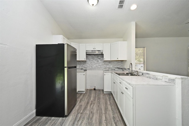 1502 W 16 Th St, Sanford, FL 32771 - kitchen with freestanding refrigerator, wood finished floors, under cabinet range hood, tasteful backsplash, and white cabinetry