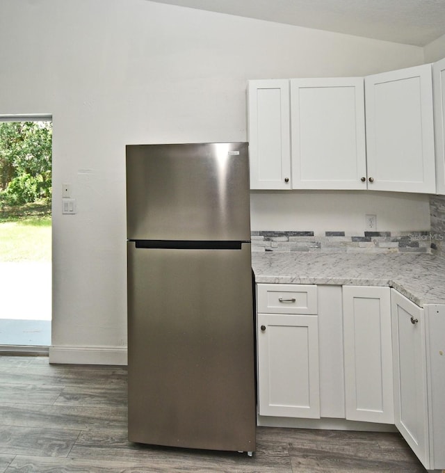 1502 W 16 Th St, Sanford, FL 32771 - kitchen with freestanding refrigerator, lofted ceiling, white cabinets, wood finished floors, and light stone countertops