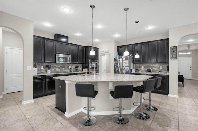 1270 Fountain Coin Loop, Orlando, FL 32828 - kitchen featuring stainless steel appliances, dark cabinetry, tasteful backsplash, an island with sink, and recessed lighting