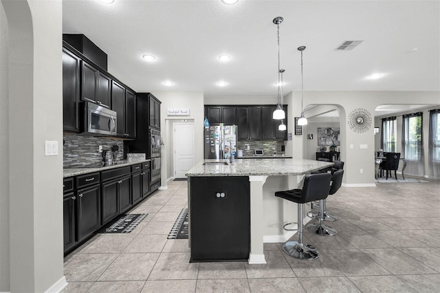 1270 Fountain Coin Loop, Orlando, FL 32828 - kitchen with stainless steel appliances, dark cabinetry, arched walkways, decorative backsplash, and recessed lighting