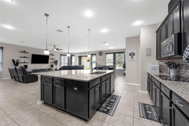 1270 Fountain Coin Loop, Orlando, FL 32828 - kitchen featuring appliances with stainless steel finishes, open floor plan, a kitchen island with sink, dark cabinets, and tasteful backsplash