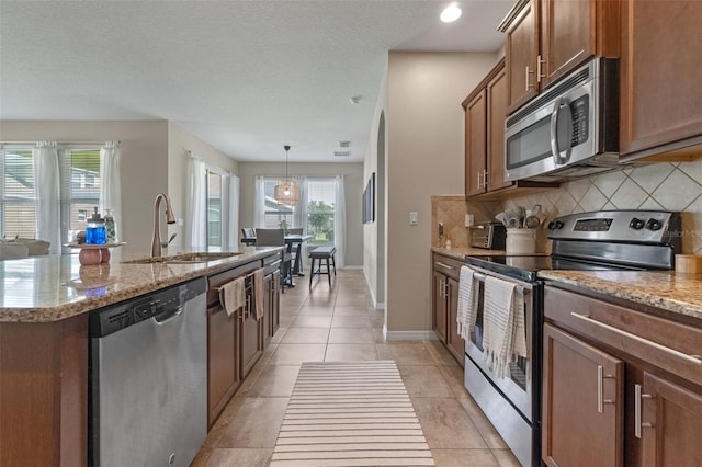 1958 Commander Way, Kissimmee, FL 34746 - kitchen with stainless steel appliances, tasteful backsplash, a kitchen island with sink, light stone counters, and a textured ceiling