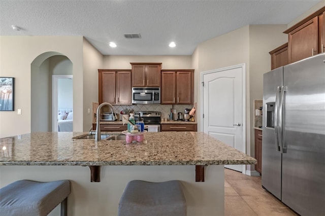1958 Commander Way, Kissimmee, FL 34746 - kitchen with stainless steel appliances, arched walkways, a kitchen breakfast bar, light stone counters, and tasteful backsplash