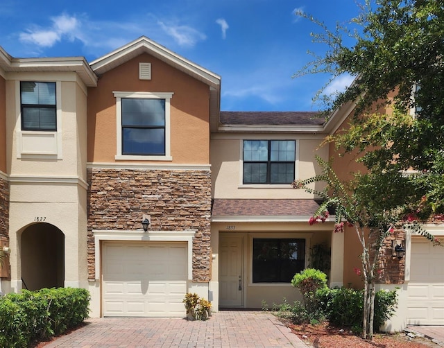 1833 Portofino Meadows Blvd, Orlando, FL 32824 - townhome / multi-family property featuring stucco siding, stone siding, an attached garage, and decorative driveway