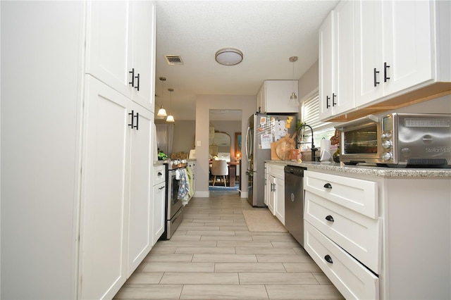 628 Riverview Ave, Altamonte Springs, FL 32714 - kitchen with stainless steel appliances, white cabinets, decorative light fixtures, light stone countertops, and light wood-style floors