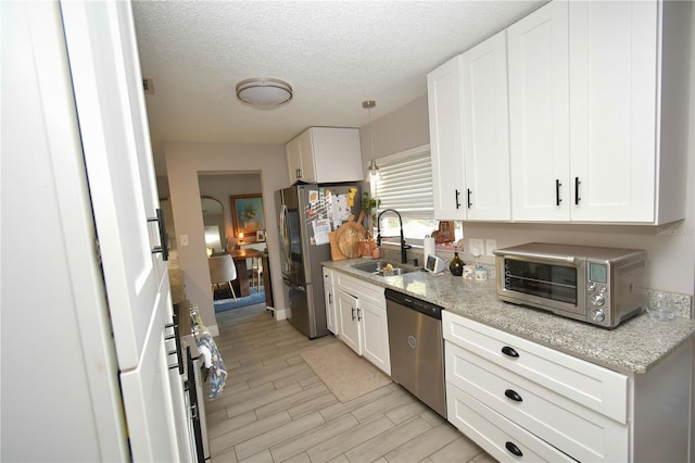 628 Riverview Ave, Altamonte Springs, FL 32714 - kitchen with appliances with stainless steel finishes, white cabinetry, light wood-type flooring, and a textured ceiling