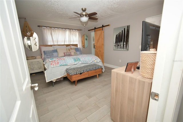 628 Riverview Ave, Altamonte Springs, FL 32714 - bedroom with a barn door, a textured ceiling, light wood-style floors, and a ceiling fan