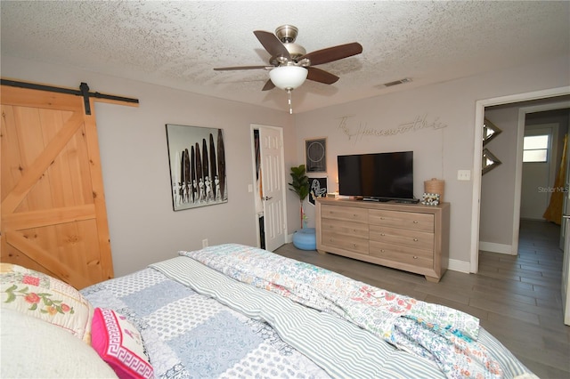 628 Riverview Ave, Altamonte Springs, FL 32714 - bedroom featuring a textured ceiling, wood finished floors, a barn door, and a ceiling fan