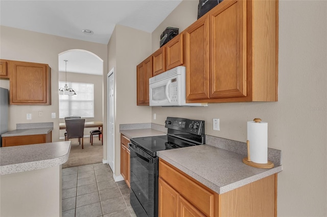 209 Grouper Ct, Poinciana, FL 34759 - kitchen with electric range, white microwave, light tile patterned floors, arched walkways, and light countertops