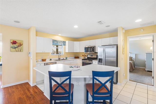 8076 SE 174th Belhaven Loop, The Villages, FL 32162 - kitchen with stainless steel appliances, light countertops, a breakfast bar area, white cabinetry, and a textured ceiling