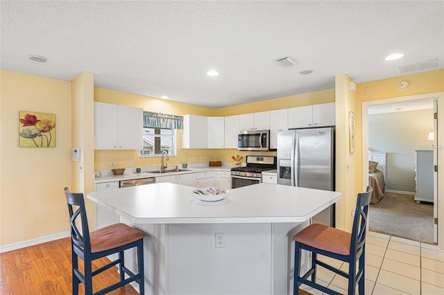 8076 SE 174th Belhaven Loop, The Villages, FL 32162 - kitchen with stainless steel appliances, a breakfast bar area, light countertops, white cabinets, and a center island
