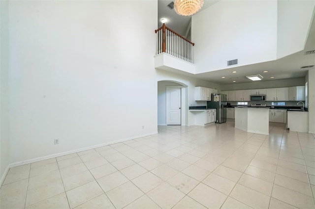 7716 Nottinghill Sky Dr, Apollo Beach, FL 33572 - unfurnished living room with light tile patterned flooring, a towering ceiling, and arched walkways