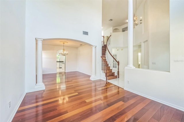 7716 Nottinghill Sky Dr, Apollo Beach, FL 33572 - spare room with a chandelier, a high ceiling, wood finished floors, arched walkways, and stairway