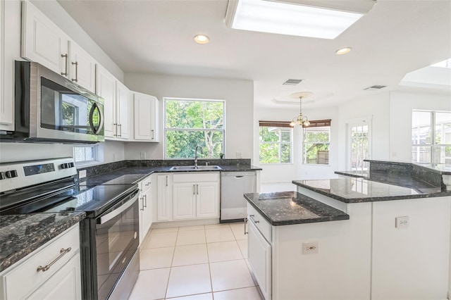 7716 Nottinghill Sky Dr, Apollo Beach, FL 33572 - kitchen with stainless steel appliances, white cabinetry, dark stone countertops, light tile patterned floors, and recessed lighting