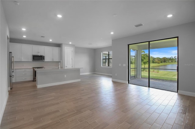 6256 Baywood Ct, Bradenton, FL 34211 - unfurnished living room featuring light wood-style floors, recessed lighting, and a water view