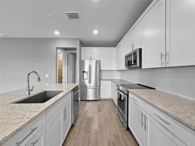 6256 Baywood Ct, Bradenton, FL 34211 - kitchen featuring appliances with stainless steel finishes, white cabinets, light wood-style floors, light stone counters, and recessed lighting