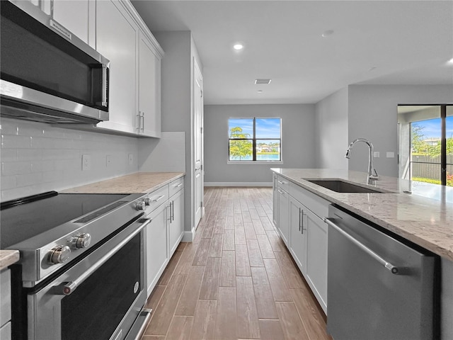 6256 Baywood Ct, Bradenton, FL 34211 - kitchen with appliances with stainless steel finishes, light wood finished floors, healthy amount of natural light, white cabinetry, and recessed lighting