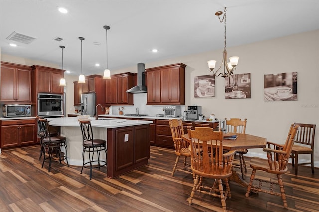 13525 Gorgona Isle Dr, Windermere, FL 34786 - kitchen with appliances with stainless steel finishes, wall chimney exhaust hood, a breakfast bar, light countertops, and recessed lighting