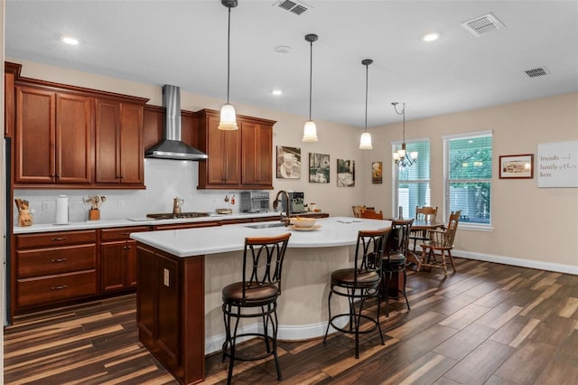 13525 Gorgona Isle Dr, Windermere, FL 34786 - kitchen with wall chimney range hood, dark wood-style floors, light countertops, an island with sink, and a breakfast bar