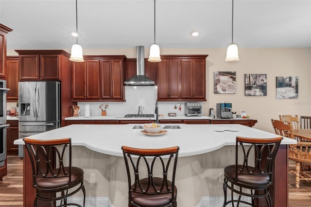 13525 Gorgona Isle Dr, Windermere, FL 34786 - kitchen featuring appliances with stainless steel finishes, wall chimney range hood, wood finished floors, light countertops, and a breakfast bar