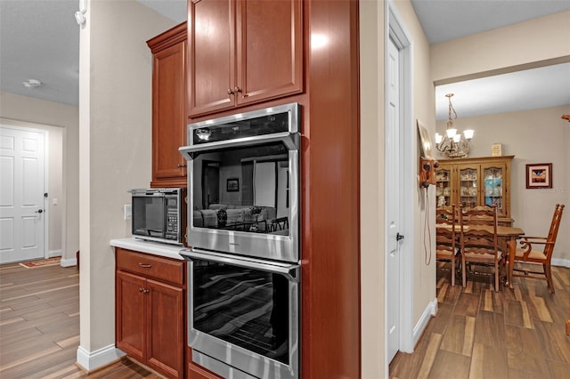 13525 Gorgona Isle Dr, Windermere, FL 34786 - kitchen featuring double oven, black microwave, a chandelier, wood finished floors, and light countertops