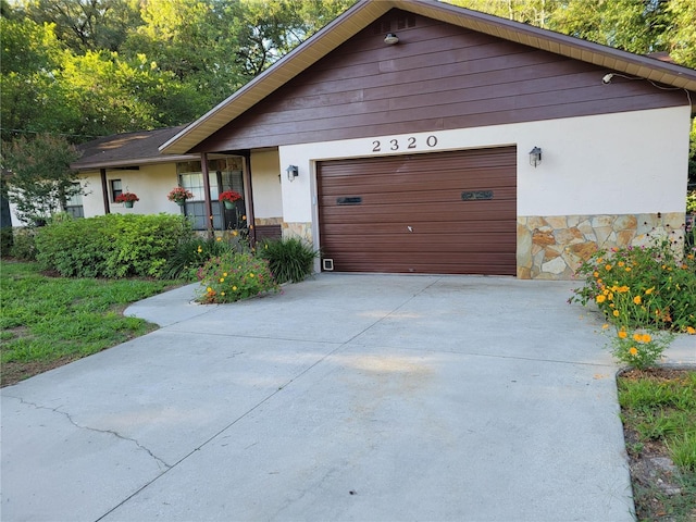 2320 NE 43rd St, Ocala, FL 34479 - view of front of home with stone siding, driveway, a garage, and stucco siding