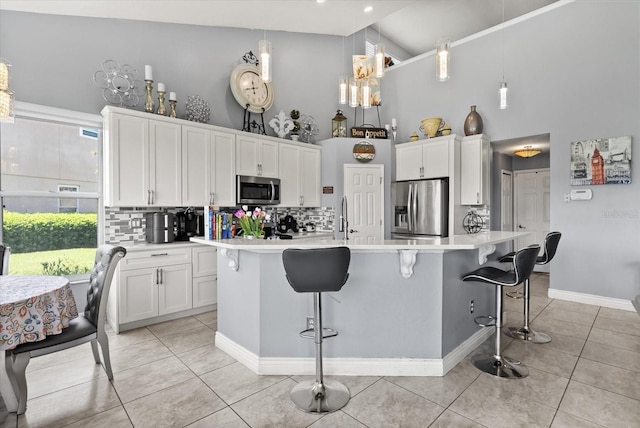 13147 Meergate Cir, Orlando, FL 32837 - kitchen featuring appliances with stainless steel finishes, high vaulted ceiling, backsplash, light tile patterned floors, and light countertops