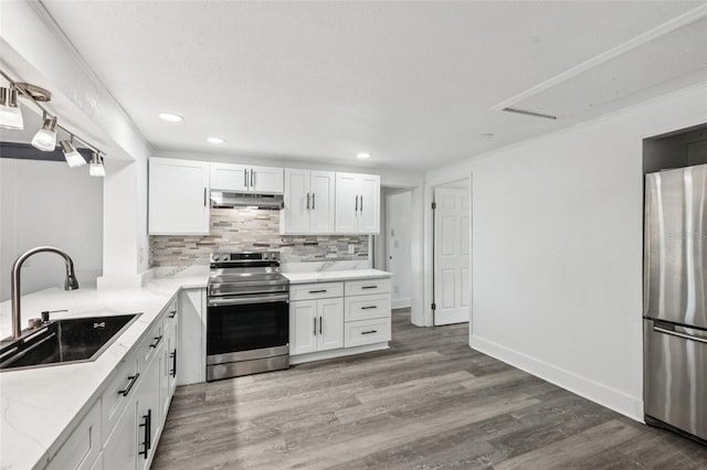 18015 Beach St, Umatilla, FL 32784 - kitchen featuring appliances with stainless steel finishes, under cabinet range hood, light wood-style flooring, decorative backsplash, and white cabinetry