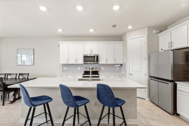 5065 Sparkling Water Way, Kissimmee, FL 34746 - kitchen with appliances with stainless steel finishes, decorative backsplash, a breakfast bar, white cabinetry, and recessed lighting