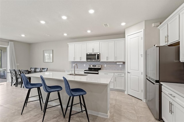 5065 Sparkling Water Way, Kissimmee, FL 34746 - kitchen featuring stainless steel appliances, a breakfast bar, decorative backsplash, recessed lighting, and white cabinets