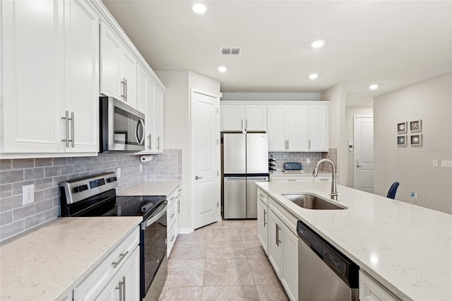 5065 Sparkling Water Way, Kissimmee, FL 34746 - kitchen featuring appliances with stainless steel finishes, decorative backsplash, white cabinetry, light stone countertops, and recessed lighting