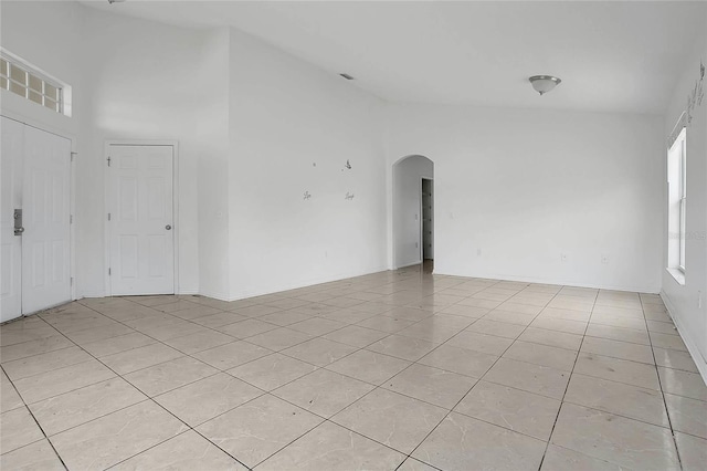 118 Sir Phillips Dr, Davenport, FL 33837 - empty room with light tile patterned floors, arched walkways, and a high ceiling