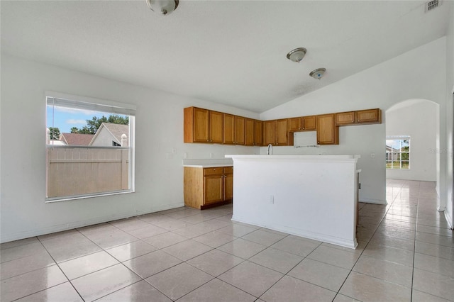 118 Sir Phillips Dr, Davenport, FL 33837 - kitchen with brown cabinetry, arched walkways, plenty of natural light, lofted ceiling, and light countertops