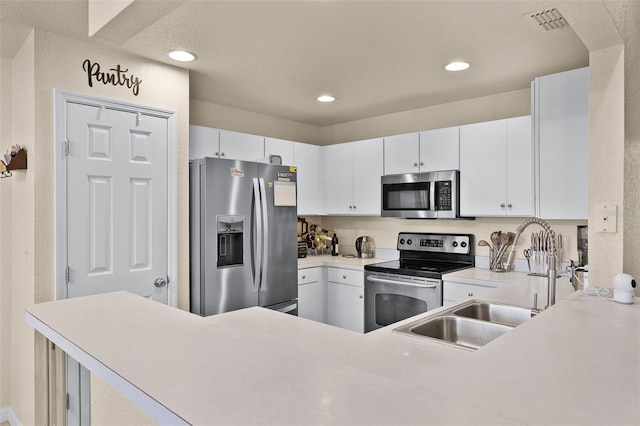 141 Winsor Ave, Davenport, FL 33837 - kitchen featuring appliances with stainless steel finishes, light countertops, recessed lighting, white cabinetry, and a peninsula