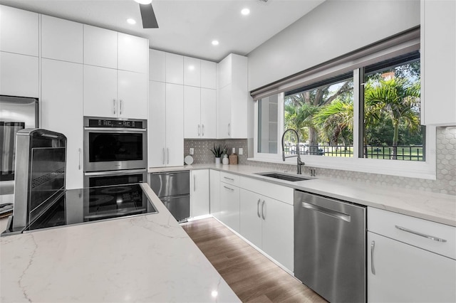 9353 Gotha Rd, Windermere, FL 34786 - kitchen featuring stainless steel appliances, decorative backsplash, light stone counters, white cabinetry, and recessed lighting