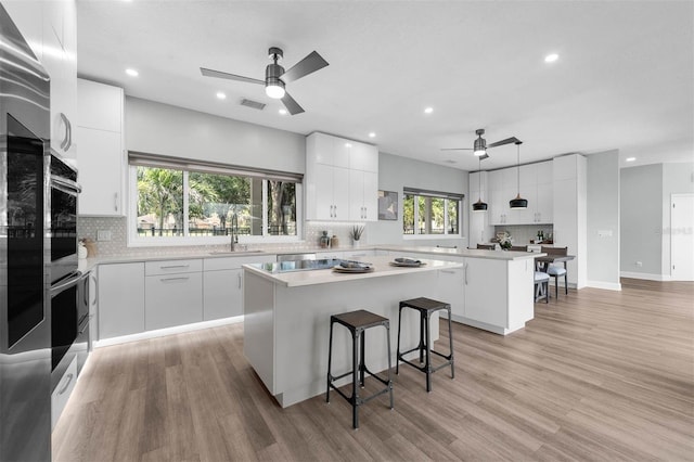 9353 Gotha Rd, Windermere, FL 34786 - kitchen with a kitchen island, ceiling fan, a kitchen breakfast bar, tasteful backsplash, and recessed lighting