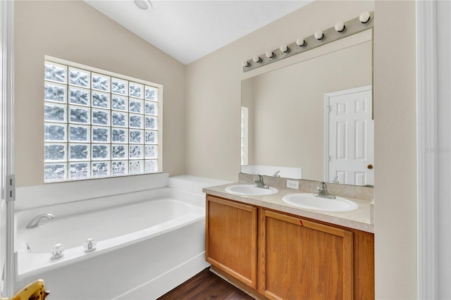 1753 Sage Creek Ct, Orlando, FL 32824 - bathroom featuring double vanity, a garden tub, lofted ceiling, and wood finished floors