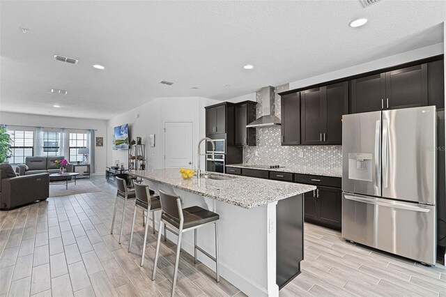461 Diamond Dove Cv, Winter Springs, FL 32708 - kitchen featuring stainless steel appliances, wall chimney exhaust hood, wood tiled floors, a kitchen island with sink, and a breakfast bar