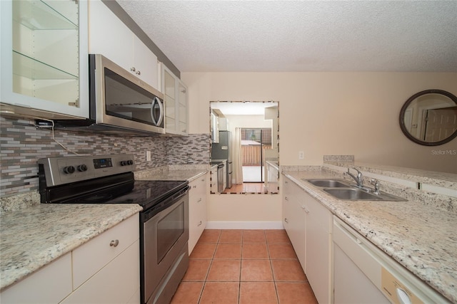 5365 Elm Ct Unit 331, Orlando, FL 32811 - kitchen with appliances with stainless steel finishes, a textured ceiling, decorative backsplash, white cabinetry, and light tile patterned floors