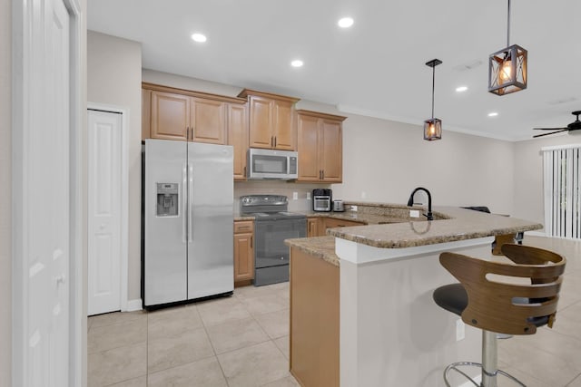 kitchen featuring appliances with stainless steel finishes, a peninsula, a kitchen bar, light stone countertops, and decorative light fixtures