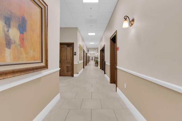 hallway featuring a drop ceiling and light tile patterned floors