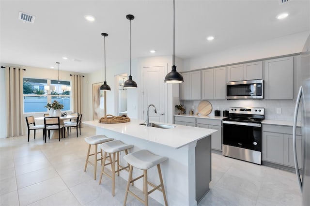 1530 Groveline Rd, Saint Cloud, FL 34771 - kitchen featuring appliances with stainless steel finishes, gray cabinetry, backsplash, light countertops, and a breakfast bar