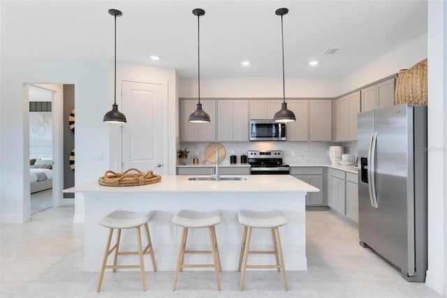 1530 Groveline Rd, Saint Cloud, FL 34771 - kitchen featuring stainless steel appliances, gray cabinets, decorative backsplash, light countertops, and a breakfast bar