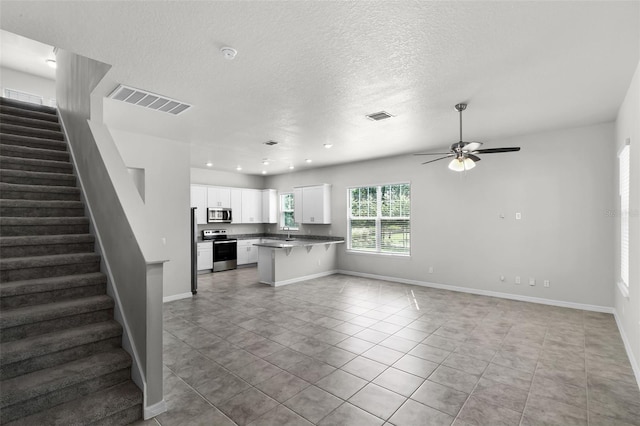 505 Venetian Palms Blvd, New Smyrna Beach, FL 32168 - kitchen featuring stainless steel appliances, open floor plan, white cabinetry, a kitchen bar, and ceiling fan